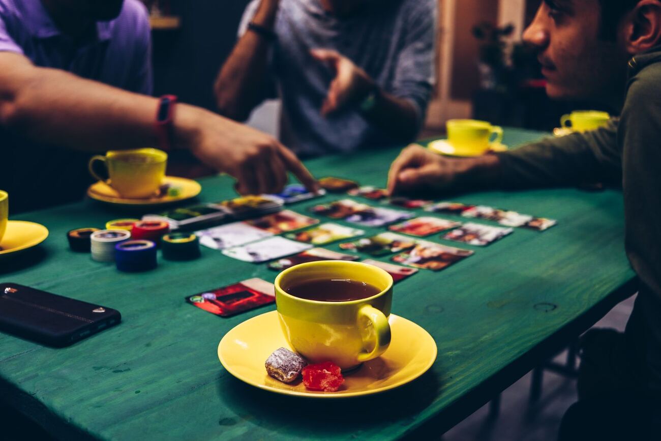 イメージ画像:卓を囲んでボードゲームを遊んでいる人たちの手元。